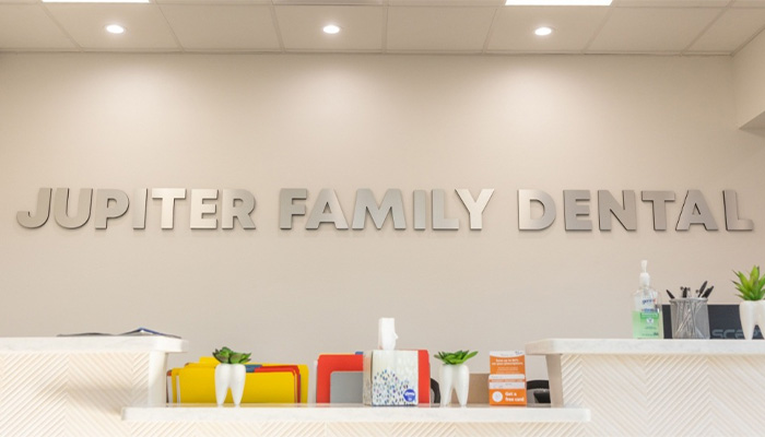 Front desk with Jupiter Family Dental spelled out on wall