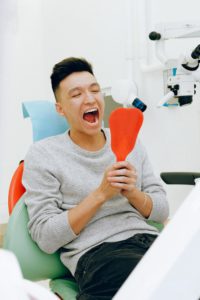 Man looking in mouth with hand mirror