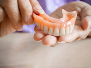 Close up of older woman holding an upper denture